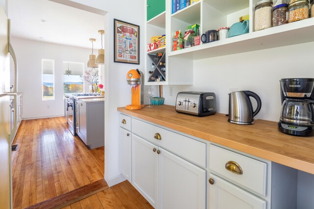 kitchen with pendant lighting, light hardwood / wood-style flooring, stainless steel range, and butcher block counters