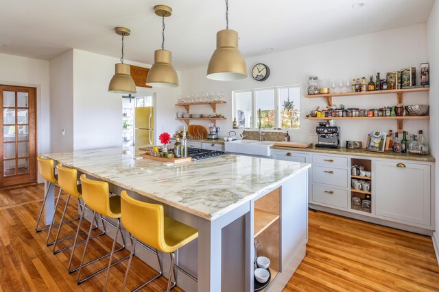 kitchen with appliances with stainless steel finishes, white cabinetry, light hardwood / wood-style floors, and a breakfast bar