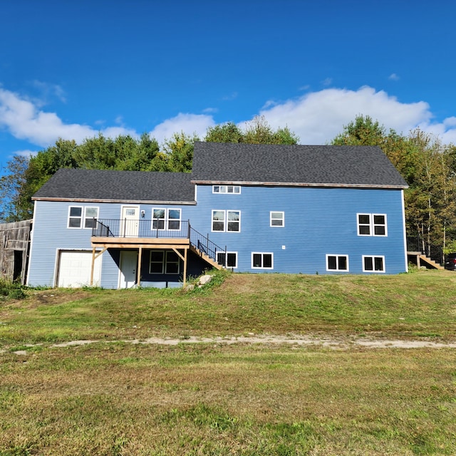 rear view of property with a lawn, a deck, and a garage