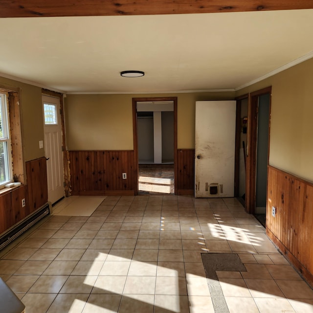 unfurnished room featuring a baseboard radiator, wood walls, light tile patterned floors, and crown molding