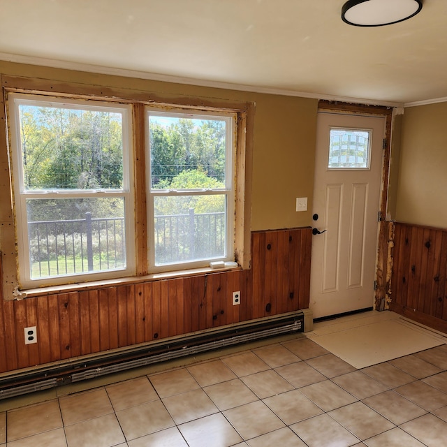 foyer featuring wooden walls, light tile patterned floors, baseboard heating, and a healthy amount of sunlight