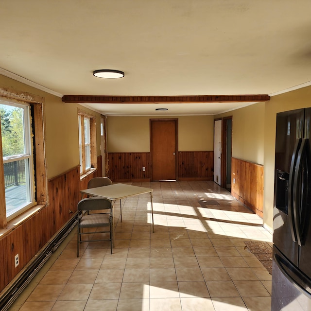 kitchen featuring crown molding, black fridge with ice dispenser, wooden walls, and baseboard heating