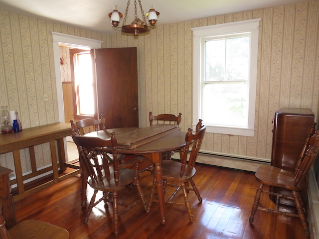 dining area with a baseboard radiator, an inviting chandelier, and dark wood-type flooring