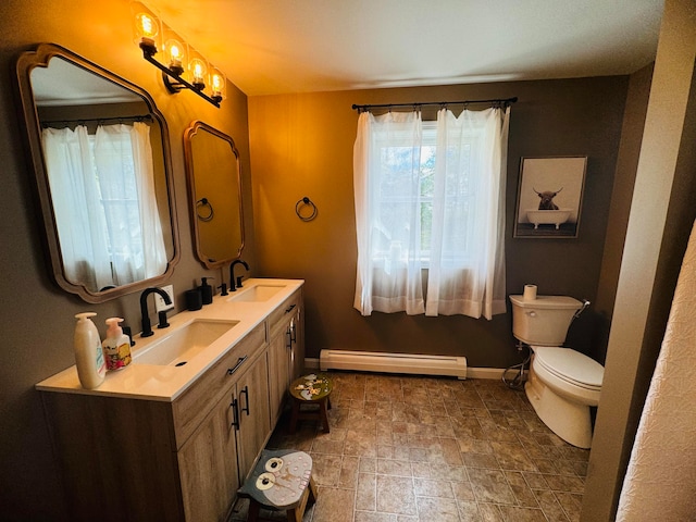 bathroom featuring a sink, a baseboard heating unit, baseboards, and toilet