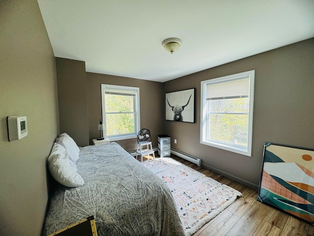 bedroom featuring wood finished floors, baseboards, and baseboard heating