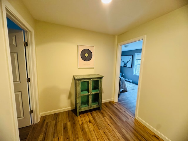 corridor featuring baseboards, wood-type flooring, and baseboard heating