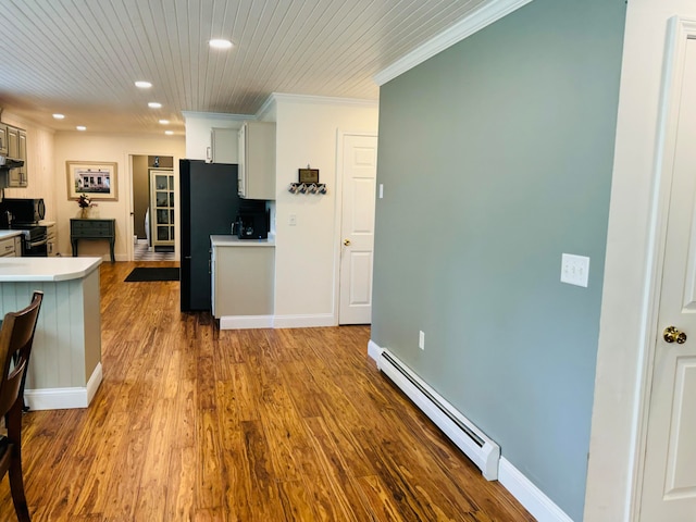 kitchen featuring a baseboard heating unit, baseboards, light countertops, ornamental molding, and wood finished floors