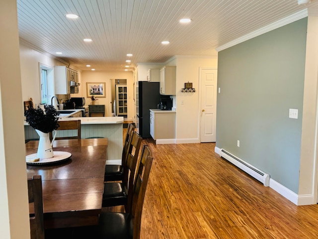 dining area featuring a baseboard heating unit, wooden ceiling, wood finished floors, and crown molding