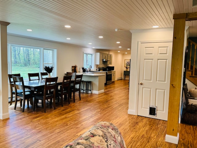 dining space featuring light wood-type flooring, ornamental molding, a baseboard heating unit, recessed lighting, and baseboards