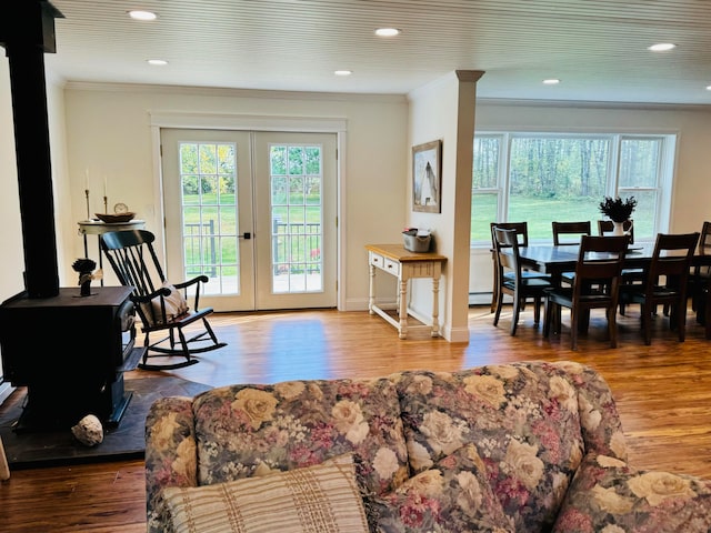 living room featuring wood finished floors, a wood stove, french doors, and crown molding