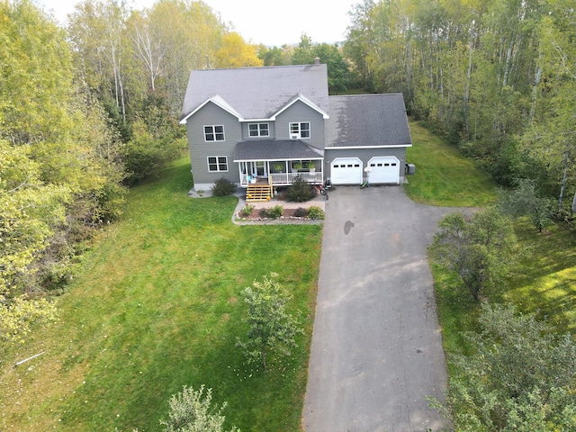 view of front facade with a front lawn, aphalt driveway, covered porch, an attached garage, and a chimney