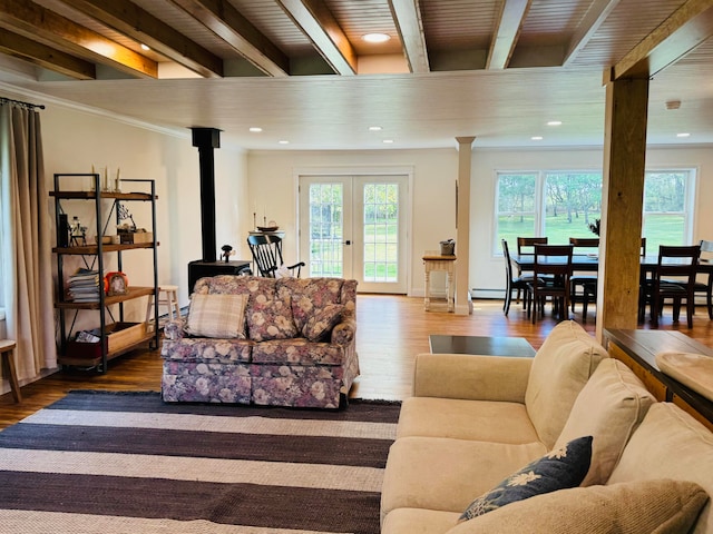 living room featuring beam ceiling, french doors, a wood stove, and wood finished floors