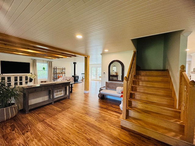 interior space featuring stairway, wood ceiling, wood finished floors, and a wood stove