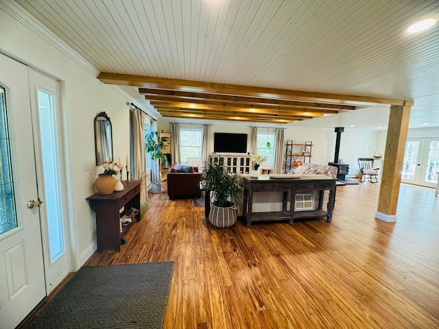 living area with beam ceiling, wood finished floors, french doors, wooden ceiling, and a wood stove