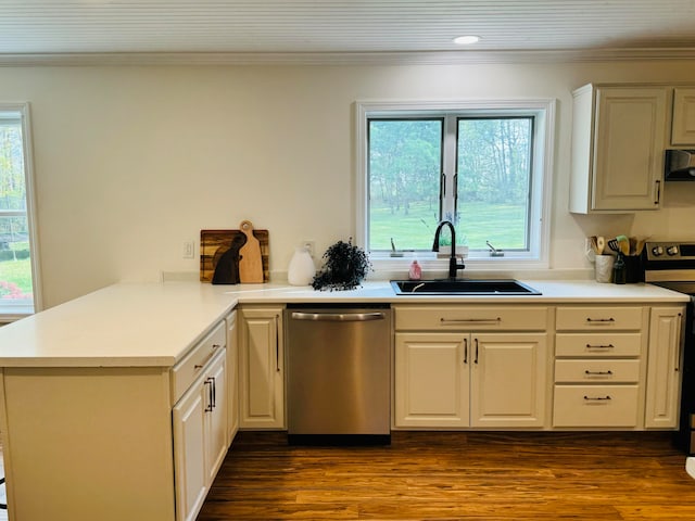 kitchen featuring crown molding, appliances with stainless steel finishes, a peninsula, dark wood-style floors, and a sink