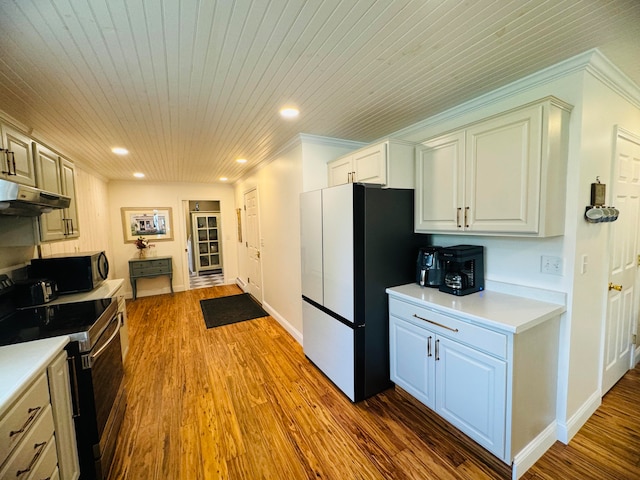 kitchen with under cabinet range hood, wood finished floors, appliances with stainless steel finishes, and light countertops