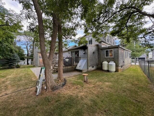 back of property with a yard, crawl space, a wooden deck, and fence