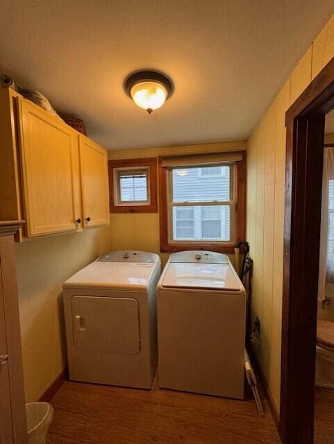 clothes washing area featuring cabinet space, washer and clothes dryer, and wood finished floors
