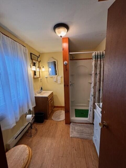bathroom featuring vanity, curtained shower, wood finished floors, a baseboard radiator, and baseboards