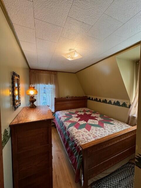 bedroom with light wood-style floors and lofted ceiling