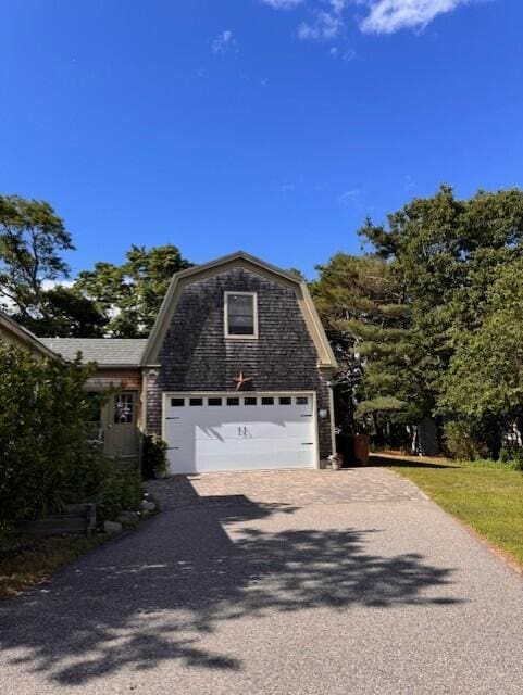view of home's exterior with a gambrel roof and driveway