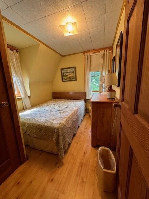 bedroom with light wood finished floors and lofted ceiling