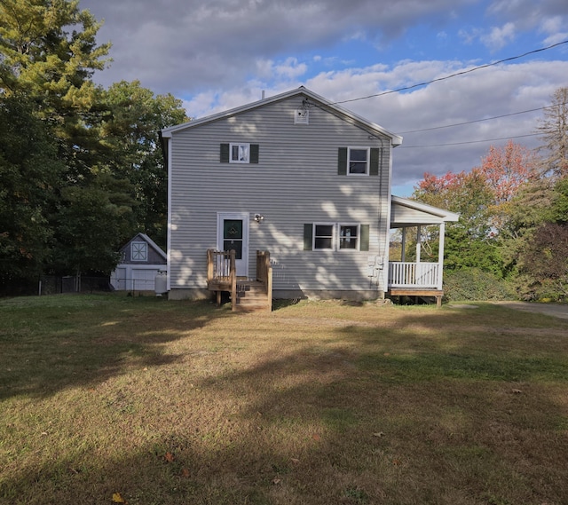 rear view of property featuring a lawn and a storage unit