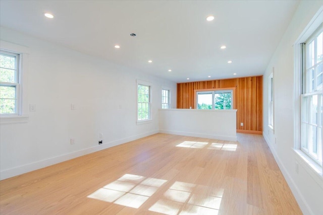 unfurnished room featuring light hardwood / wood-style floors and wooden walls