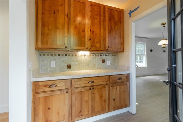 kitchen featuring decorative backsplash, light hardwood / wood-style flooring, and decorative light fixtures