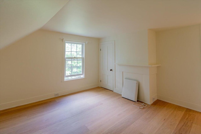 additional living space with light hardwood / wood-style flooring and vaulted ceiling