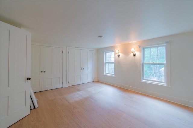 unfurnished bedroom with light wood-type flooring and two closets