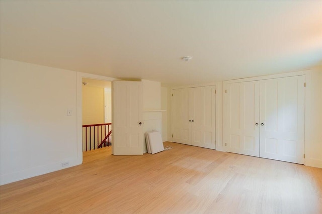 unfurnished bedroom featuring two closets and light hardwood / wood-style flooring