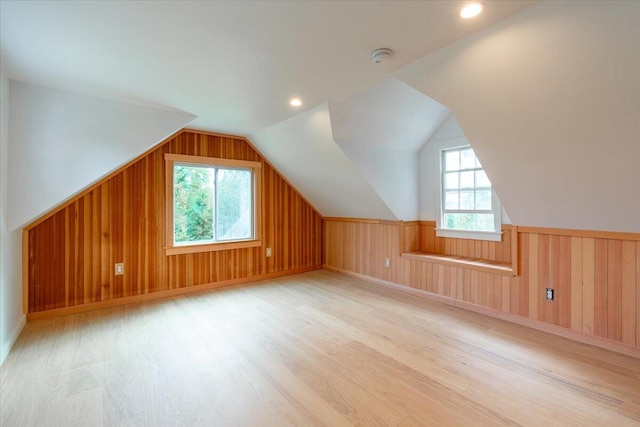 additional living space with lofted ceiling, light hardwood / wood-style floors, and wood walls