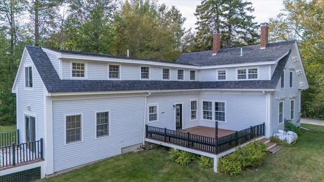 back of property featuring a wooden deck and a lawn