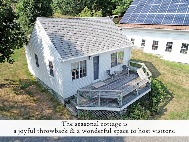 back of property with solar panels, a yard, and a wooden deck