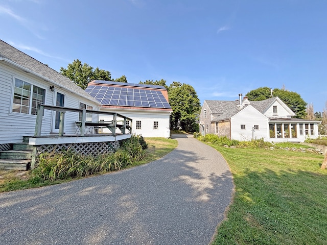 view of property exterior featuring solar panels, a deck, and a yard