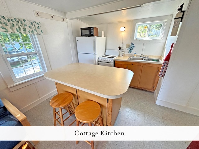 kitchen featuring white appliances, a breakfast bar area, and sink