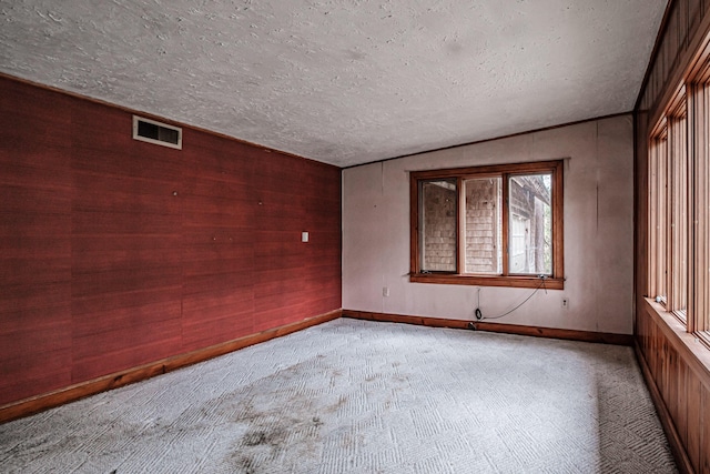 2457 Main St, Hanover, ME 04237 - empty room featuring light carpet, a textured ceiling, wood walls, and lofted ceiling