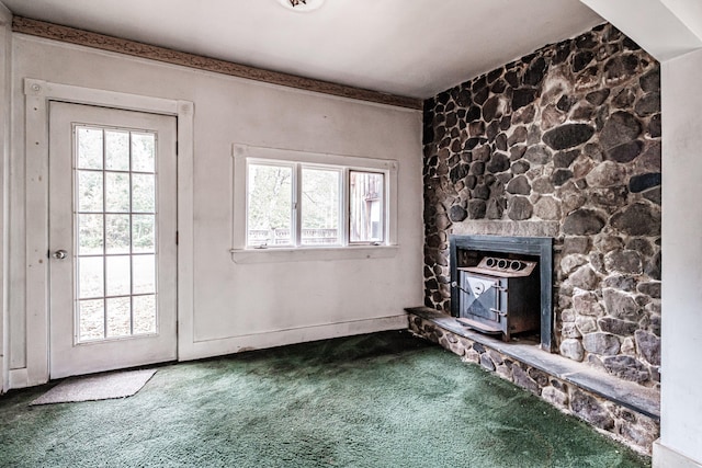 unfurnished living room with a stone fireplace, carpet flooring, and a wealth of natural light