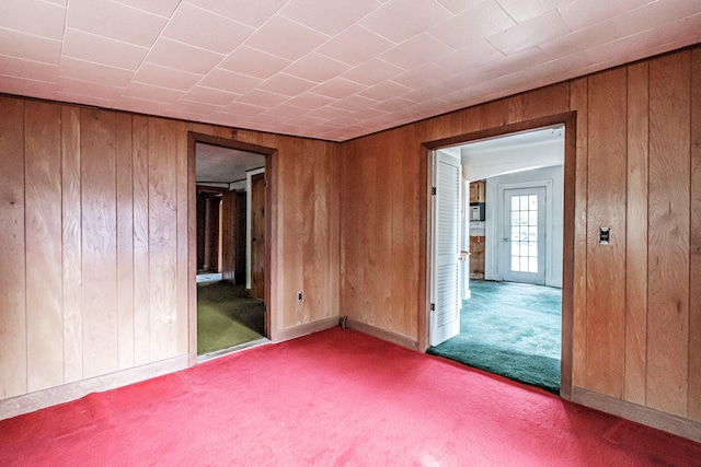 spare room featuring wooden walls and light colored carpet