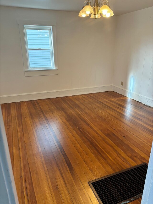 spare room featuring dark hardwood / wood-style flooring and a chandelier