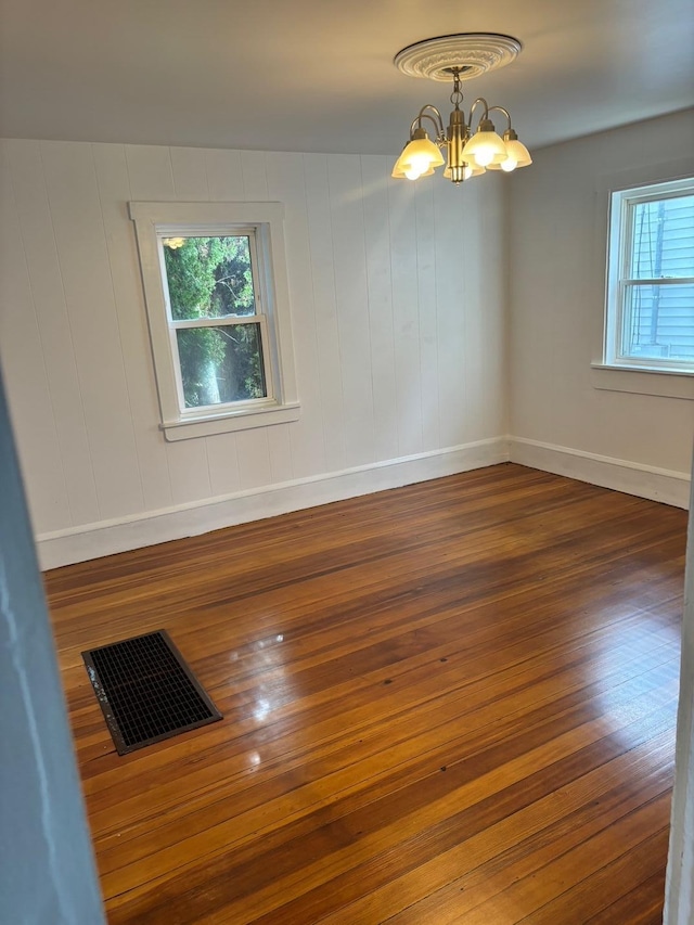 unfurnished room featuring dark hardwood / wood-style floors and a chandelier