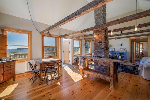 dining area featuring radiator, beam ceiling, and light hardwood / wood-style floors