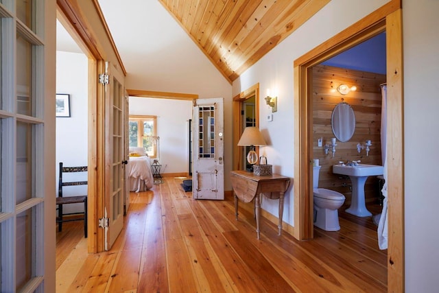 hallway featuring wood ceiling, wooden walls, vaulted ceiling, and light hardwood / wood-style floors