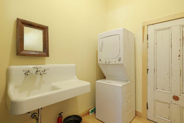 laundry area featuring light hardwood / wood-style flooring, stacked washer / drying machine, and sink