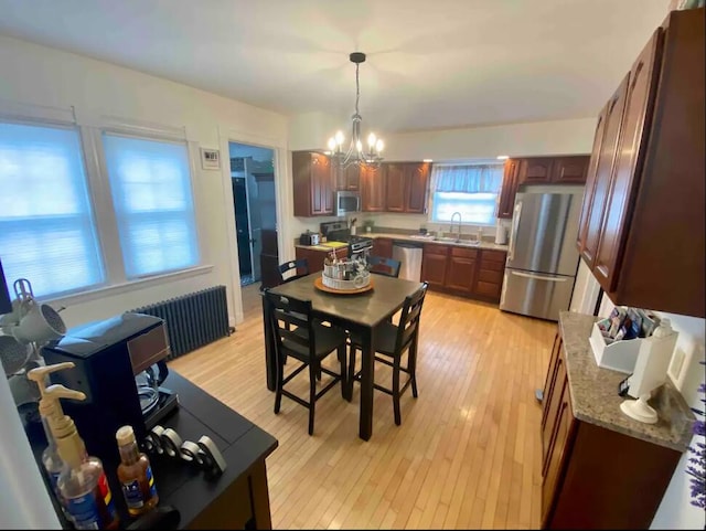 dining area featuring radiator, light wood-type flooring, a chandelier, and sink