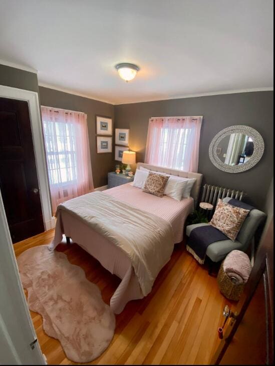 bedroom with ornamental molding, wood-type flooring, and radiator