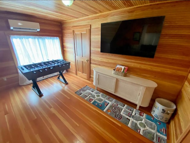 playroom featuring wood walls, a wall mounted AC, and hardwood / wood-style flooring