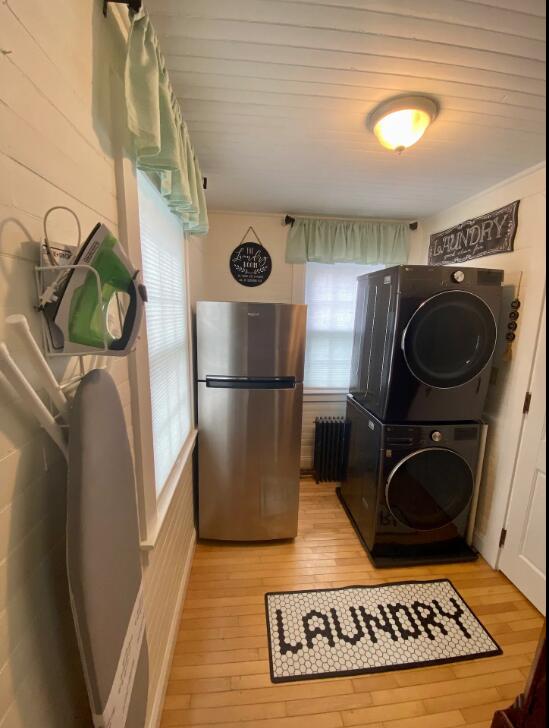 washroom featuring radiator, light wood-type flooring, and stacked washer / dryer