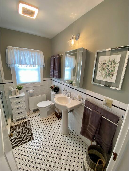 bathroom with tile walls, radiator, toilet, and tile patterned floors